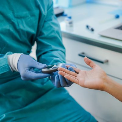 Medical doctor checking blood sugar level to young patient for diabetes disease control - Focus on woman hand